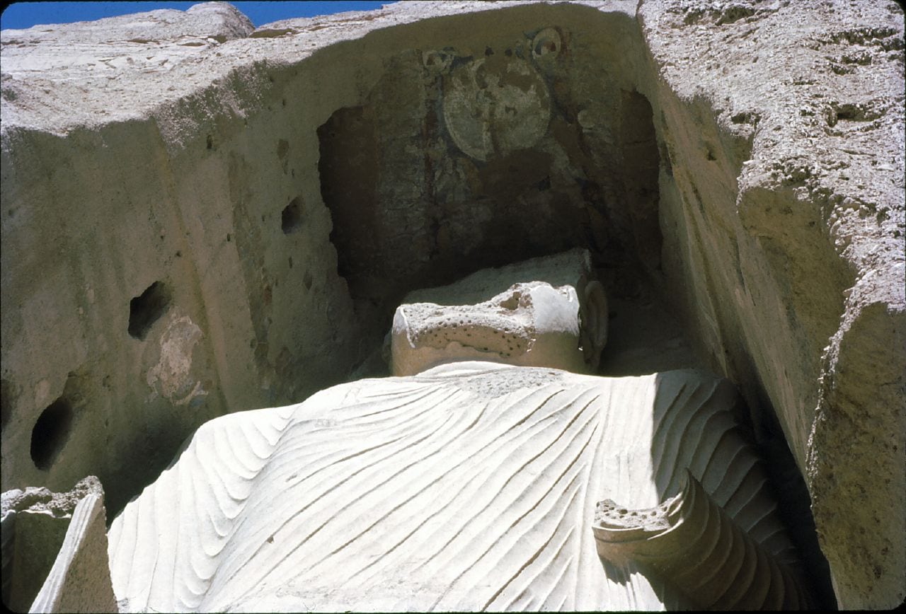 A towering empty niche cut into a sandstone cliff where a giant statue once stood