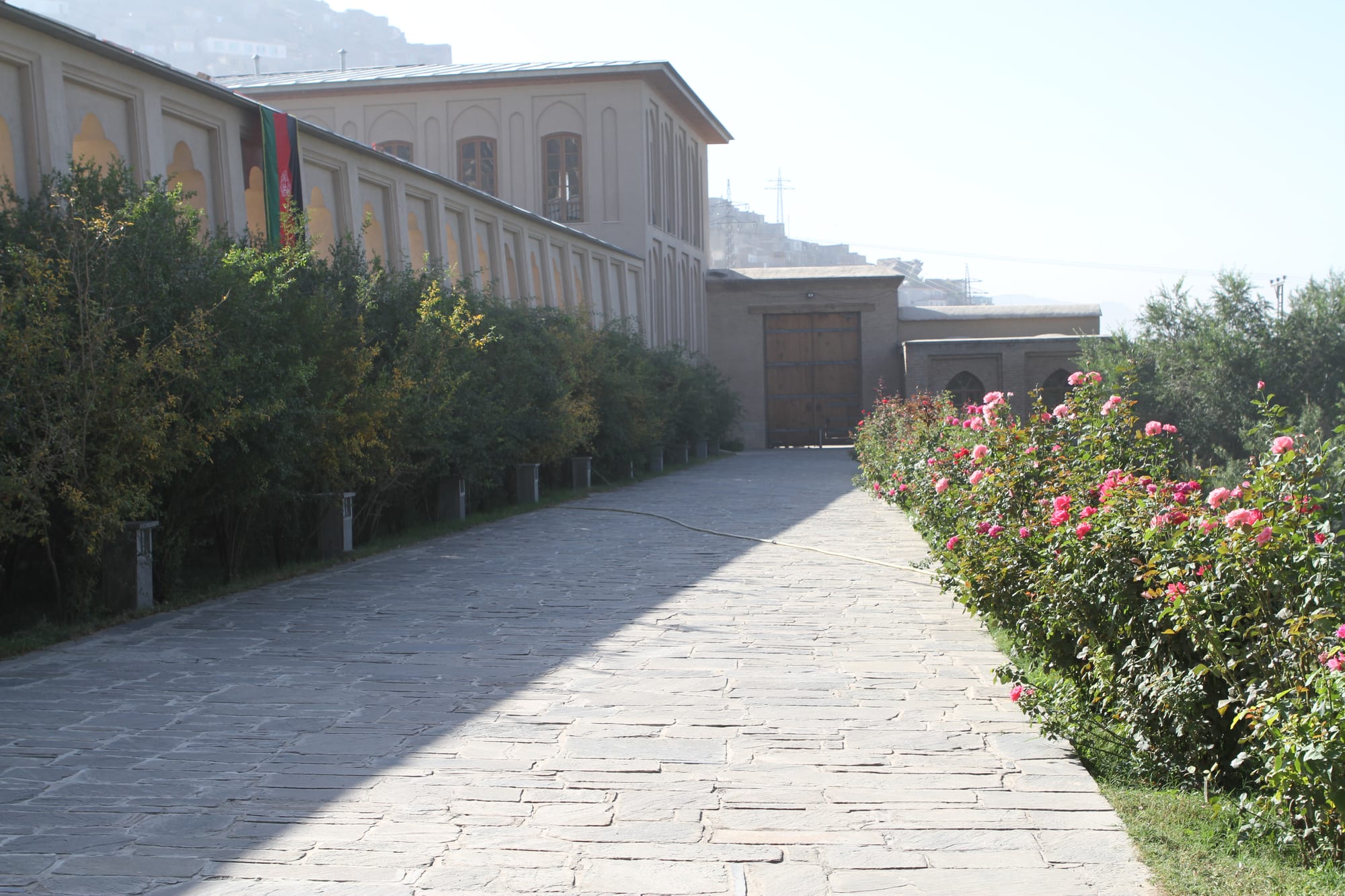 Terraced green gardens with water channels climbing a hillside toward a white marble mosque
