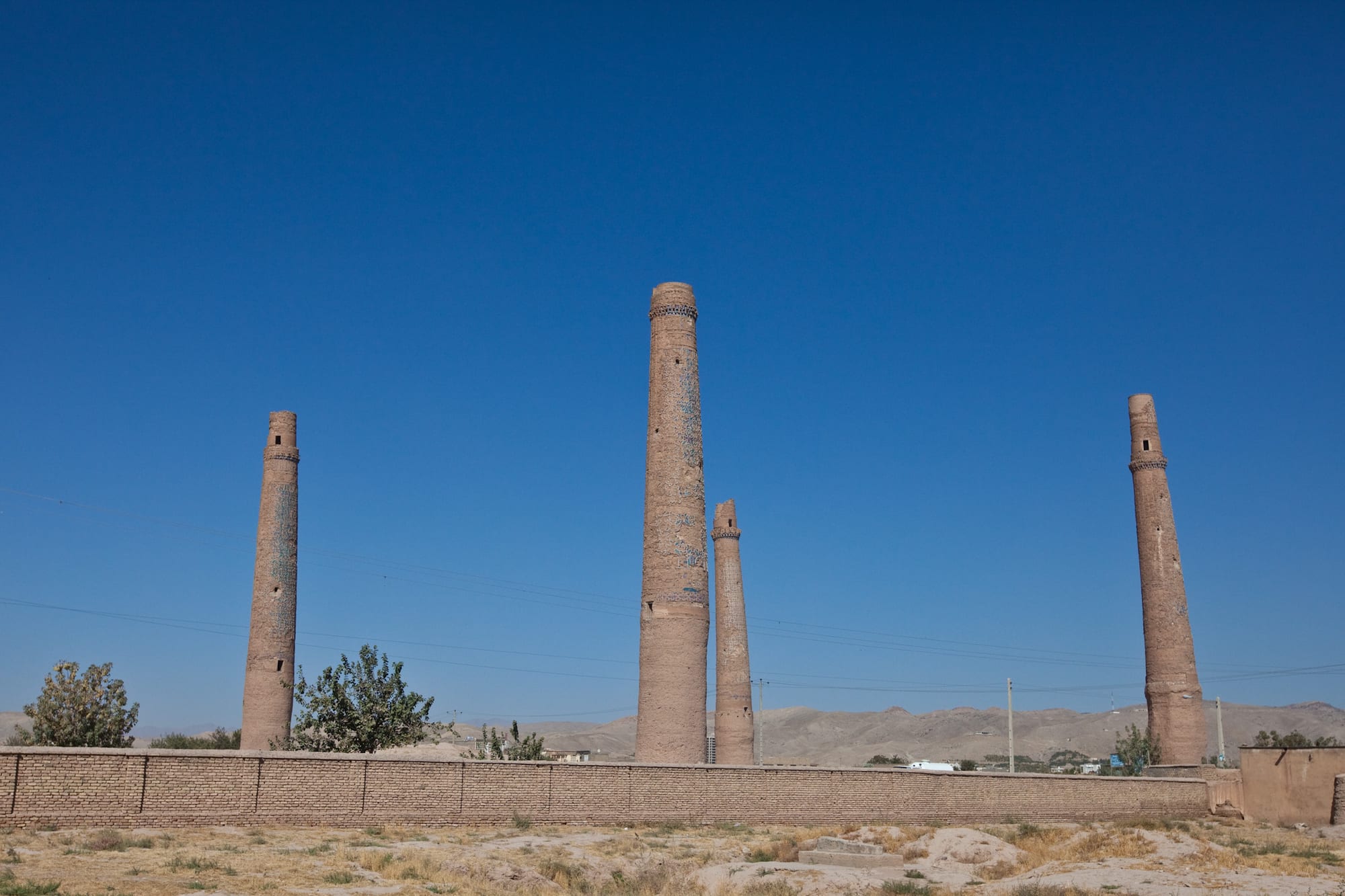 Several tall, isolated tiled minarets leaning at slight angles across an open field
