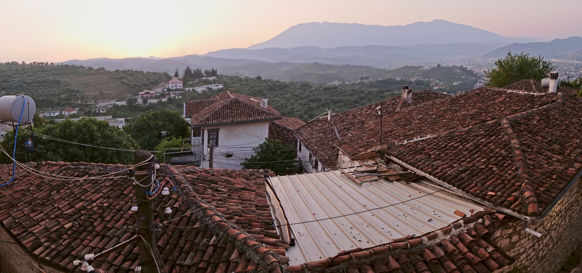 Whitewashed Ottoman houses stacked up a steep hillside below a castle at dawn