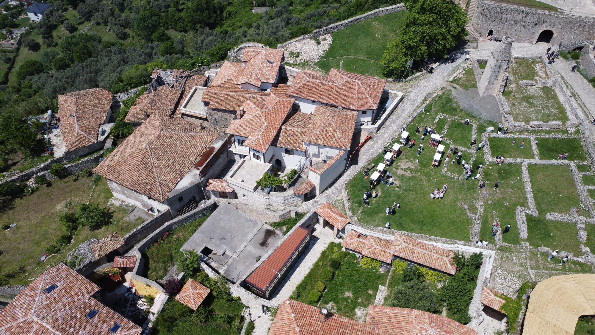 A stone castle and clock tower on a steep mountain spur, town roofs below