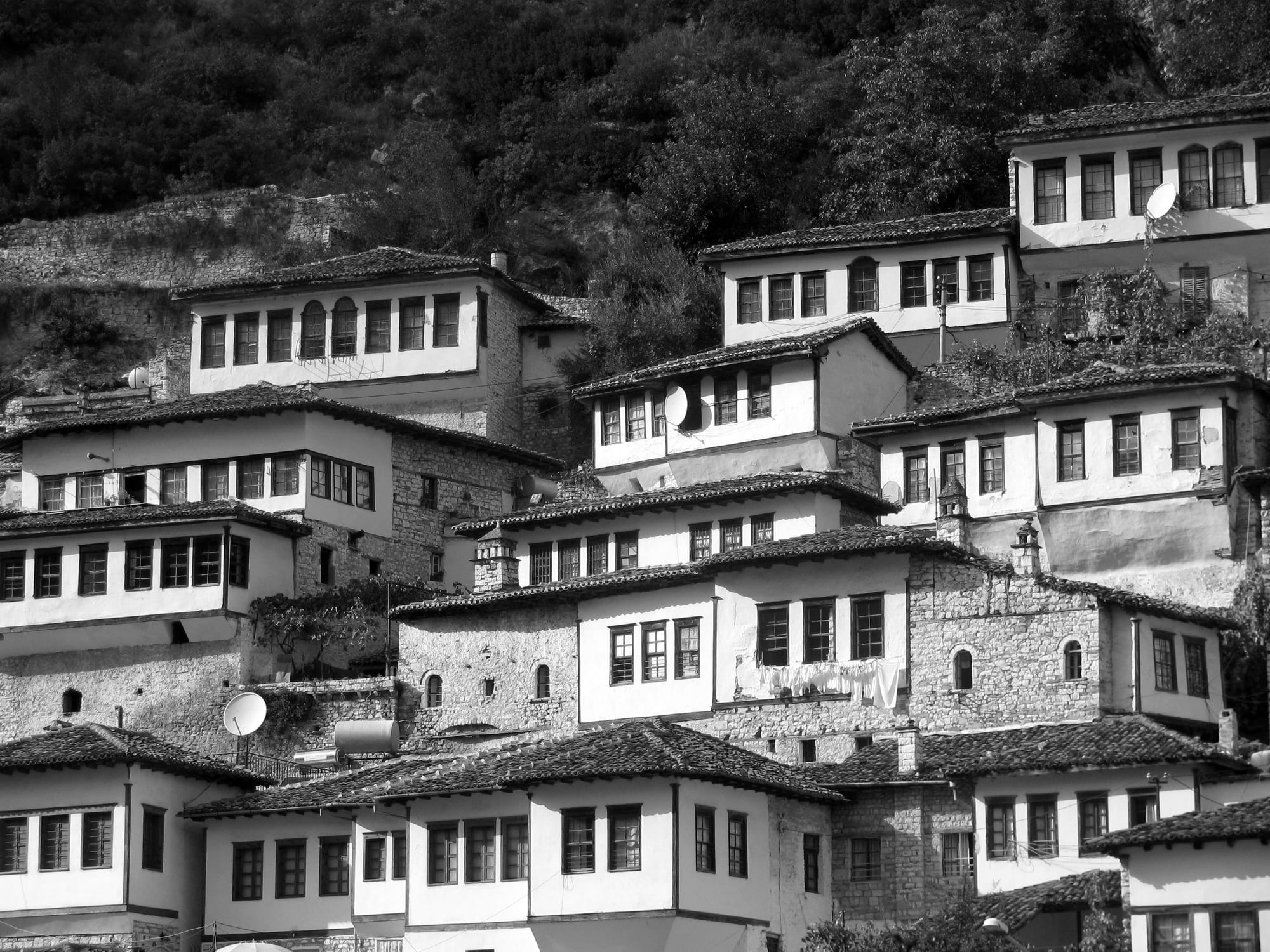 Tiers of white Ottoman-era houses with large windows climbing a steep hillside to a castle