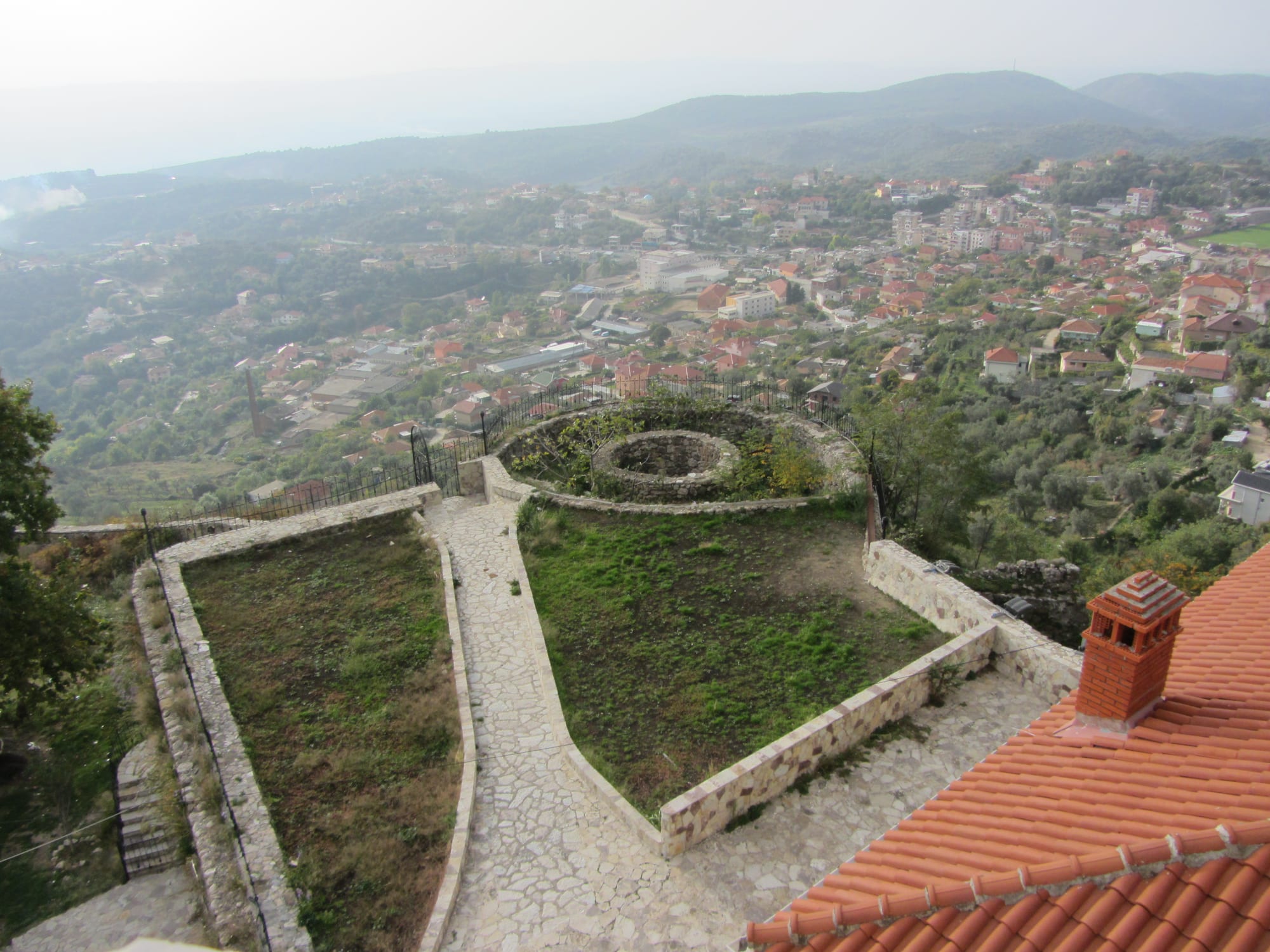 A stone hilltop castle above a white town, with mountains behind