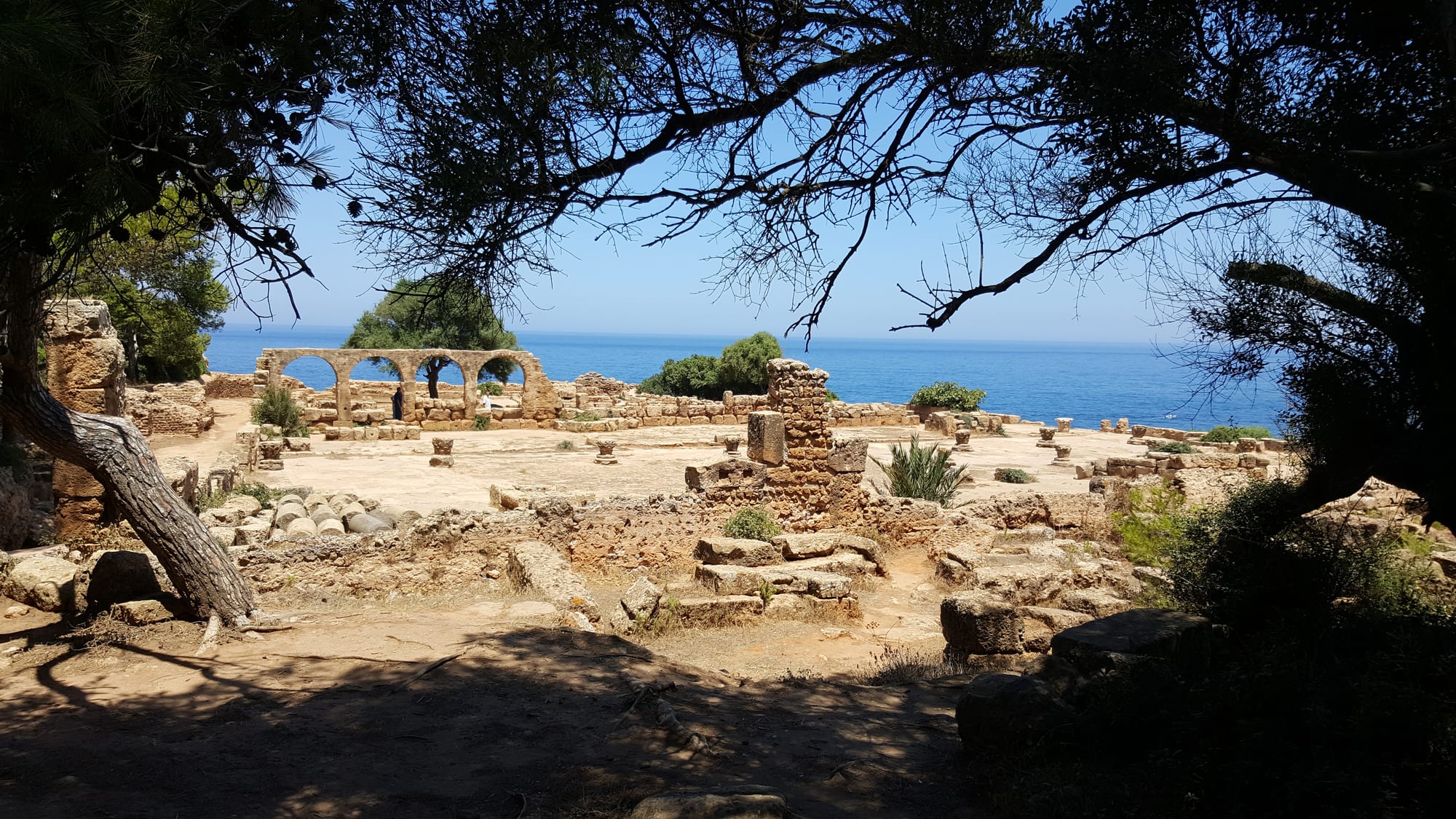Roman ruins and columns on a green headland above the Mediterranean