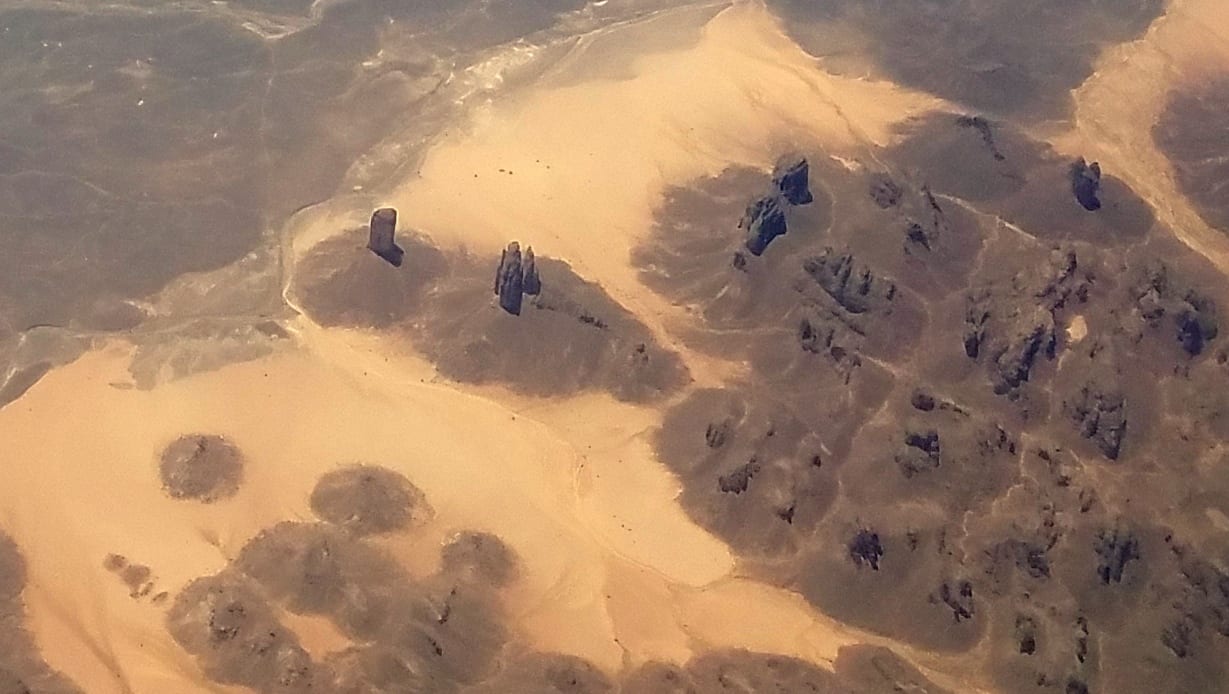Towering eroded sandstone pillars rising from desert sand under a deep blue sky