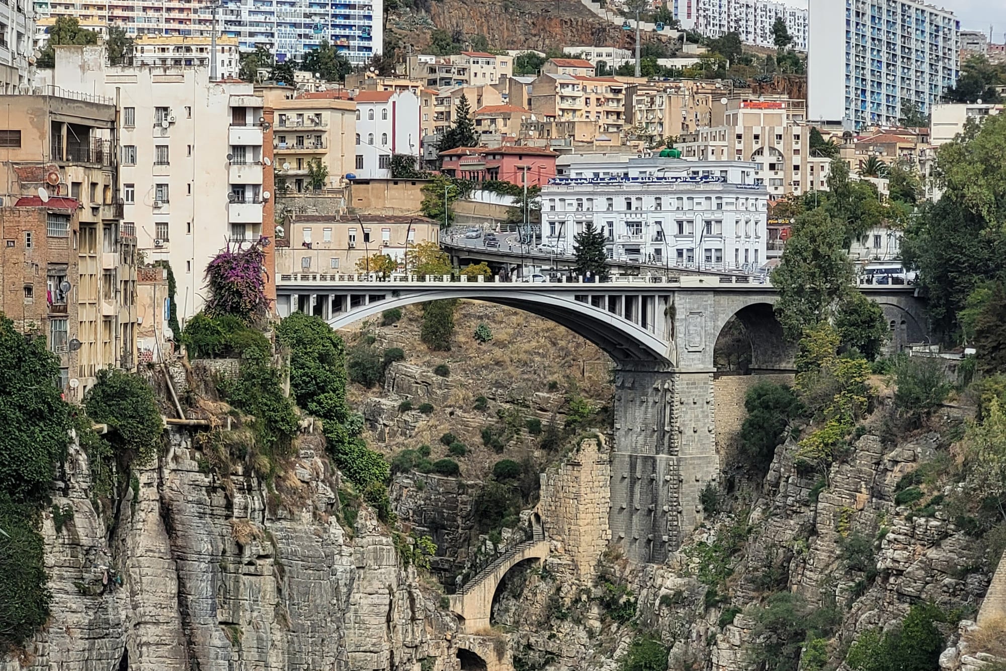 A high arched bridge spanning a deep rocky gorge with a town on the cliff edge