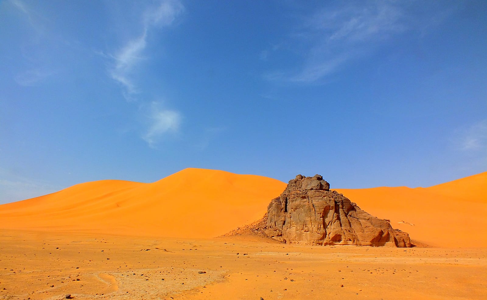 Red sand dunes threading between dark eroded sandstone massifs