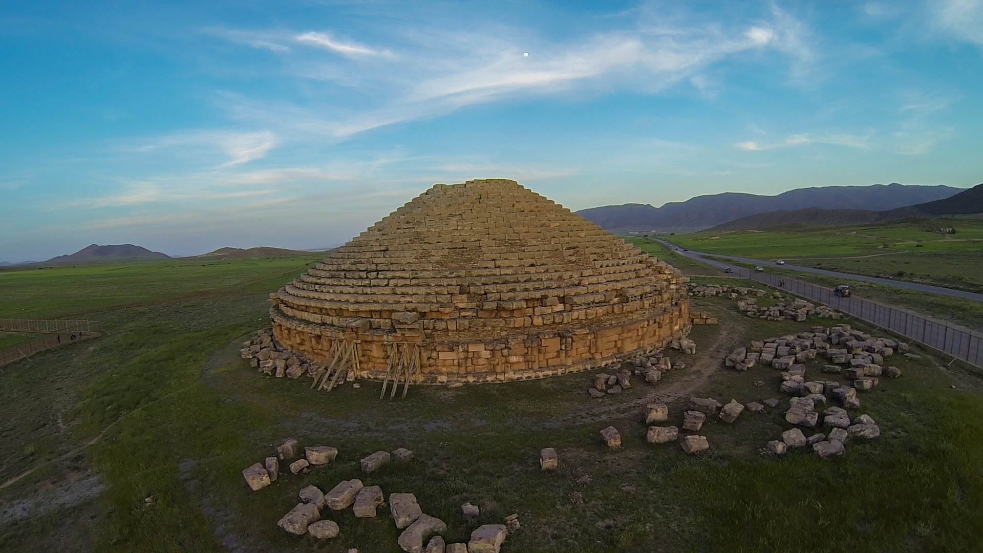 A large circular stone stepped monument with engaged columns, standing alone on a plain