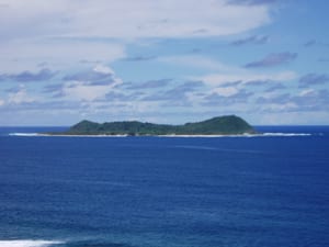 A small round island seen from the sea, covered in green forest