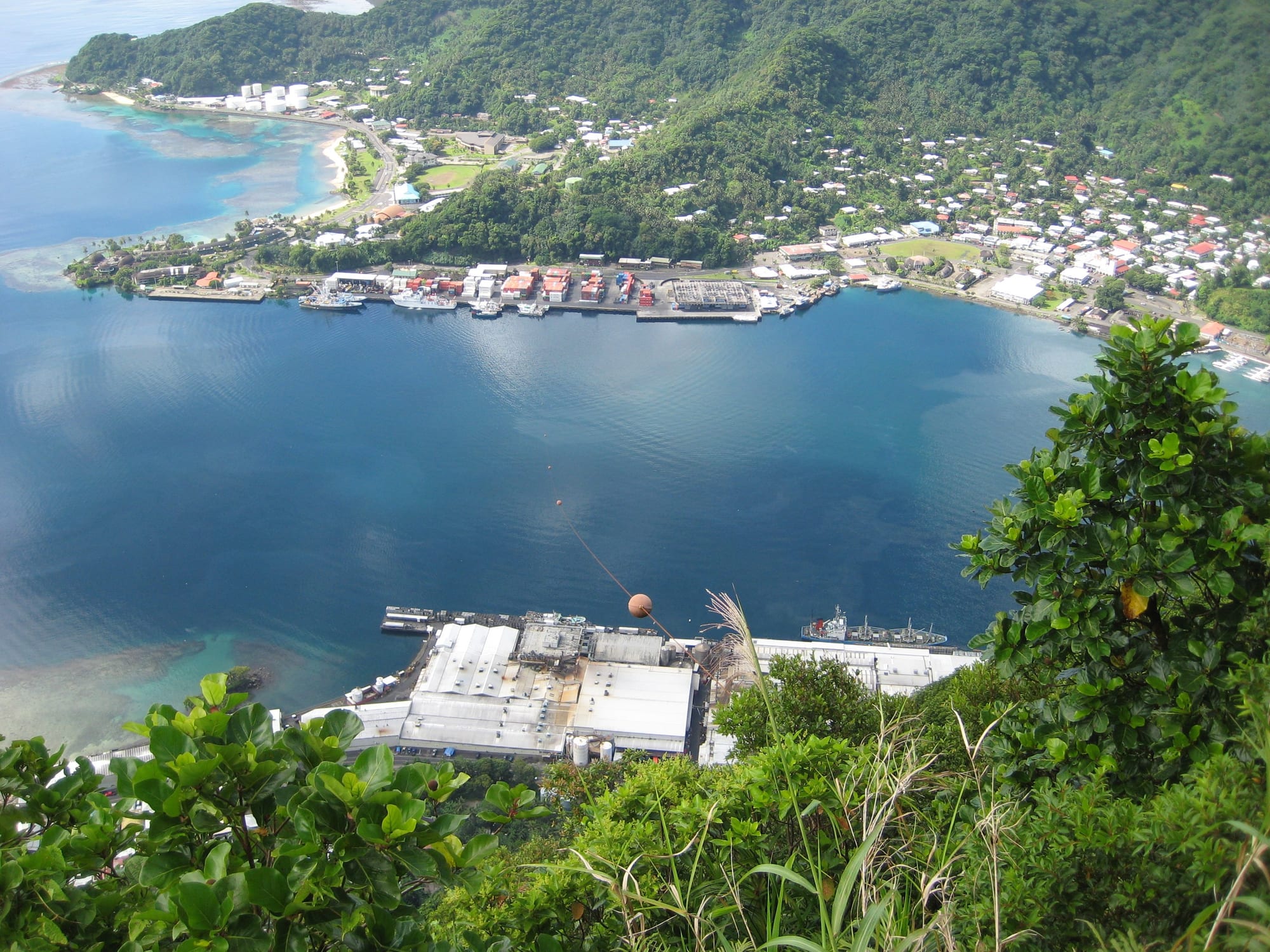 A deep blue bay ringed by steep green mountains, a small town along the shore