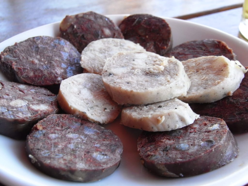 Sliced rounds of pale and dark cured sausage arranged on a white plate