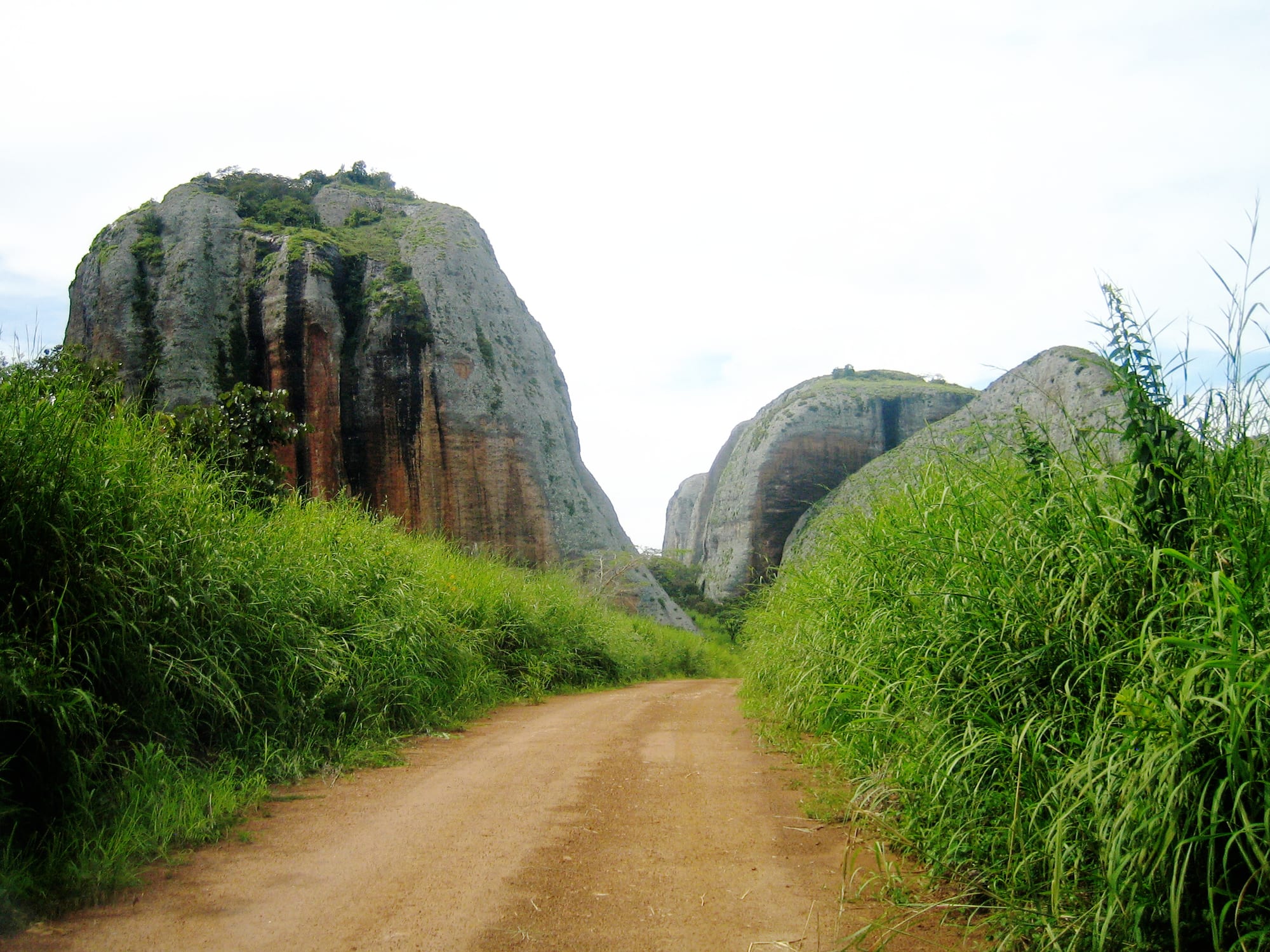 Enormous rounded dark rock formations rising abruptly from flat green grassland