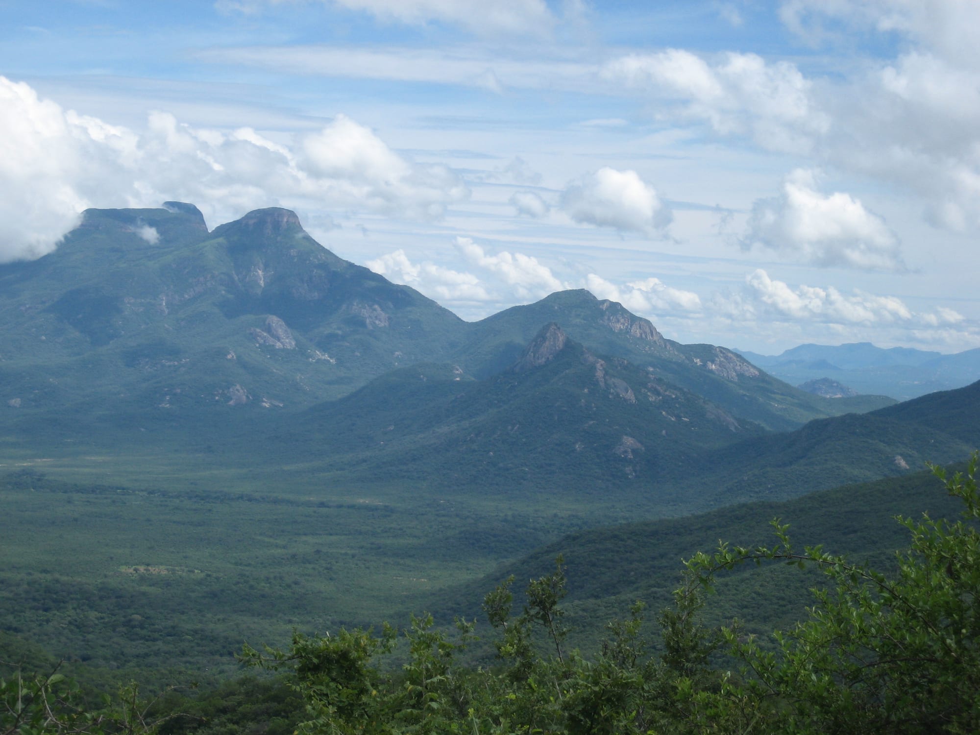 A mountain road of tight hairpin bends descending a steep green escarpment