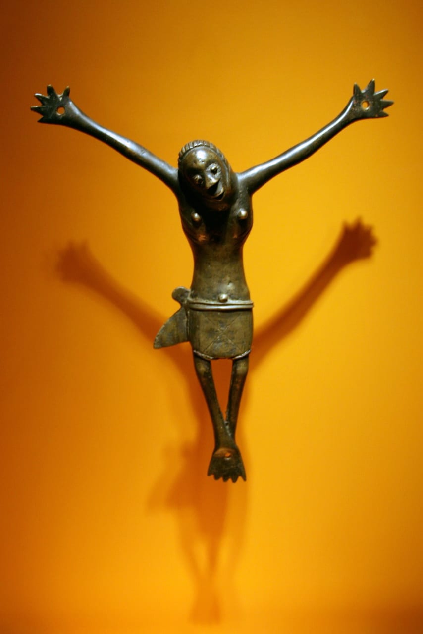A cast brass crucifix with an African-featured Christ figure and smaller praying figures at the base