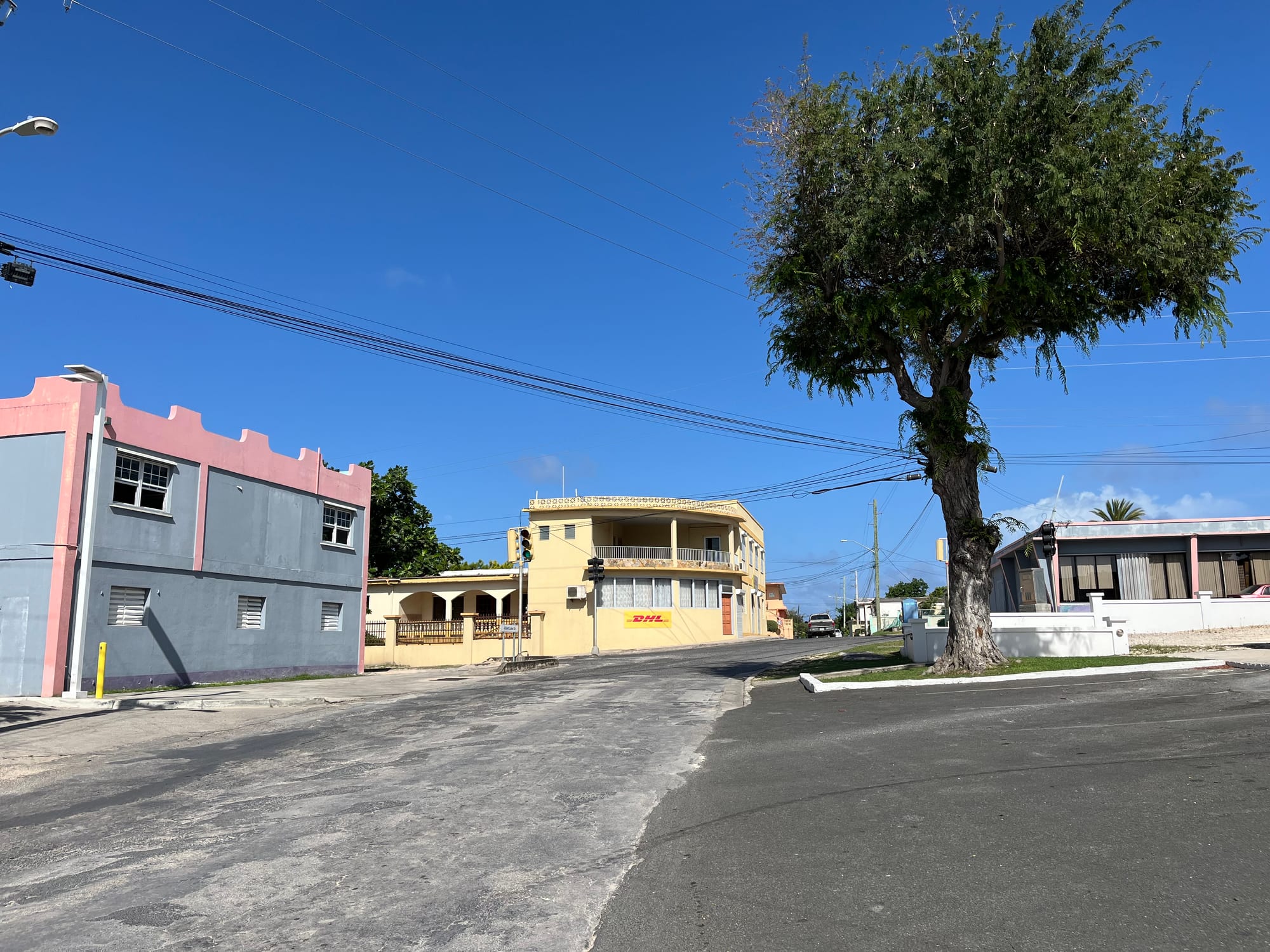 A quiet street in The Quarter, Anguilla, lined with pastel-painted two-storey buildings under a bright blue sky