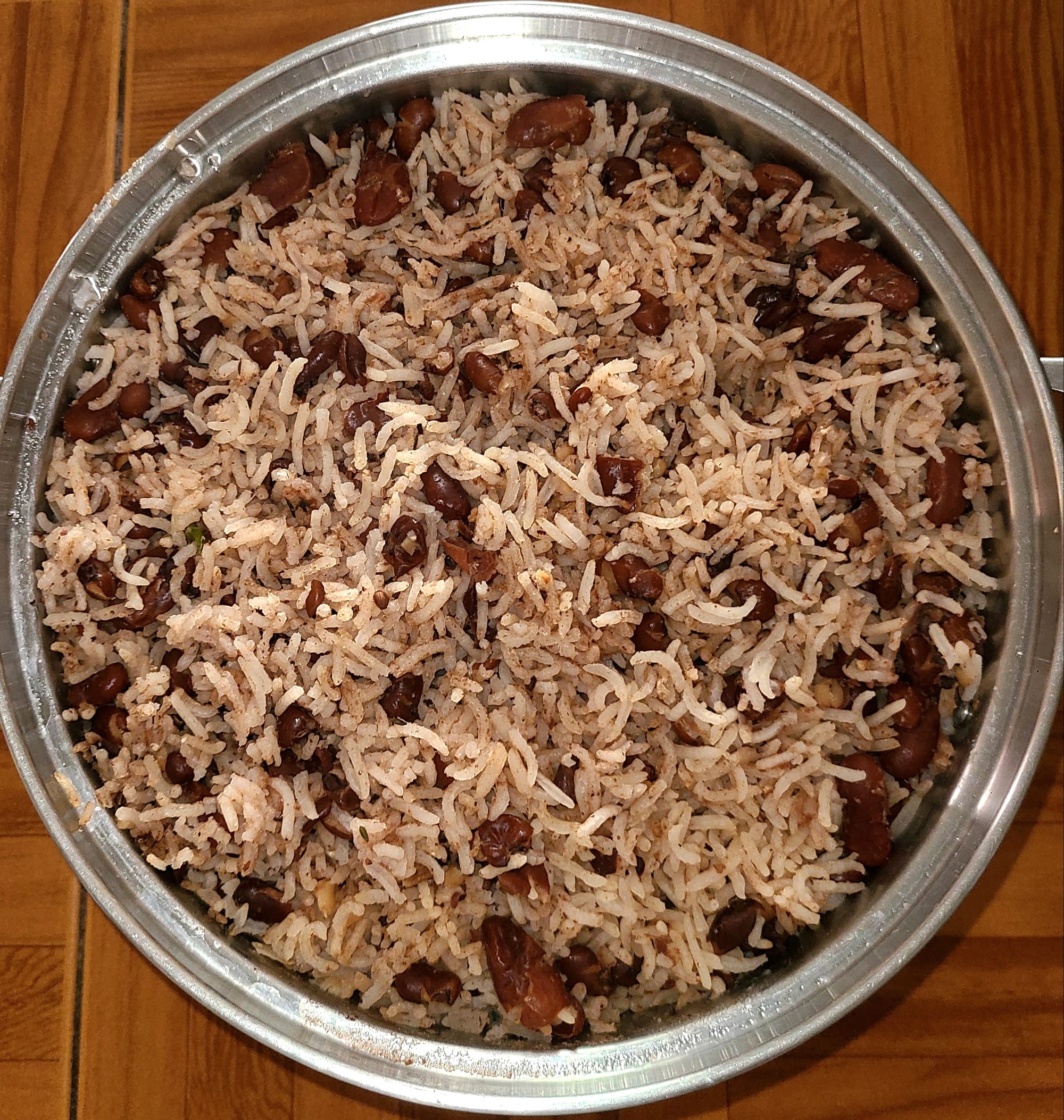 An overhead view of a large steel pot of rice cooked with dark red kidney beans