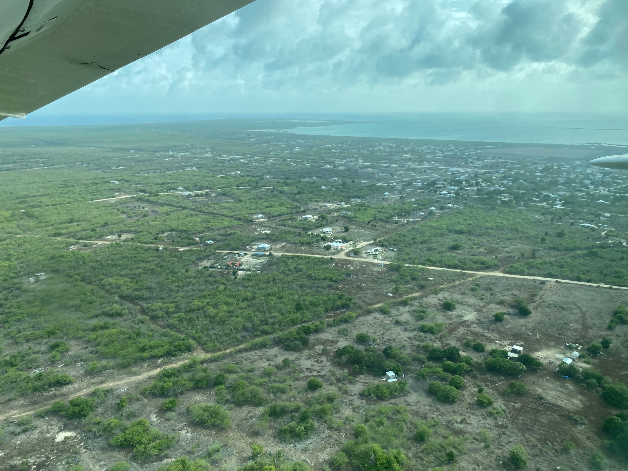 A low sandy island with a small grid-plan town beside a wide pale lagoon