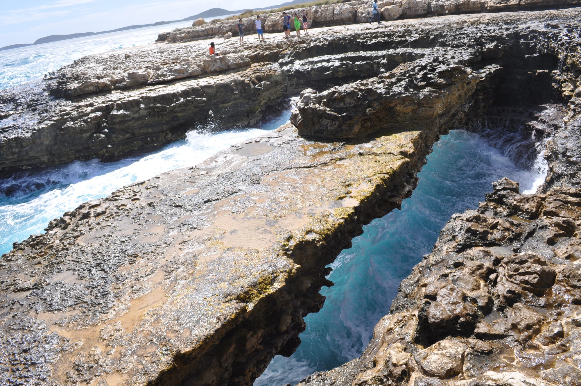 A natural rock arch over churning surf on a low limestone headland