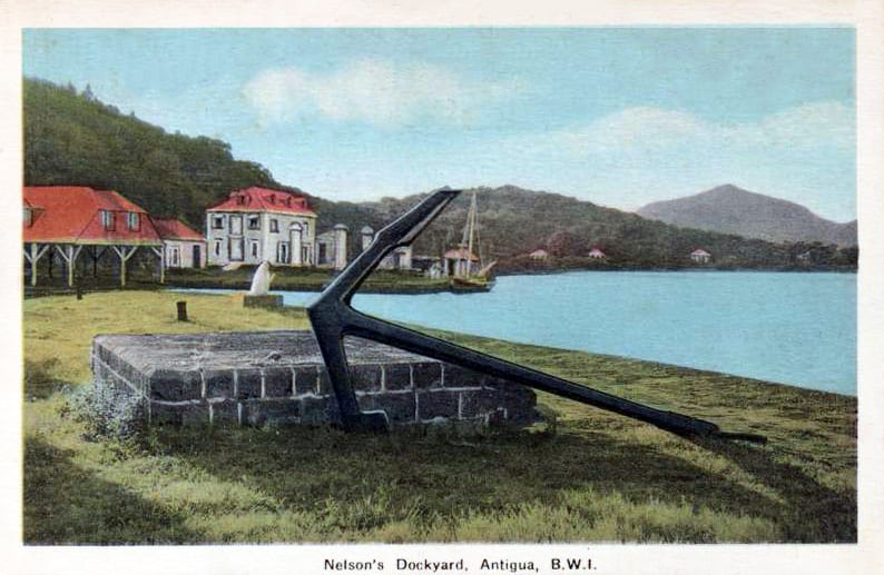 An old photograph of derelict Georgian dockyard buildings and stone pillars by a quiet harbour