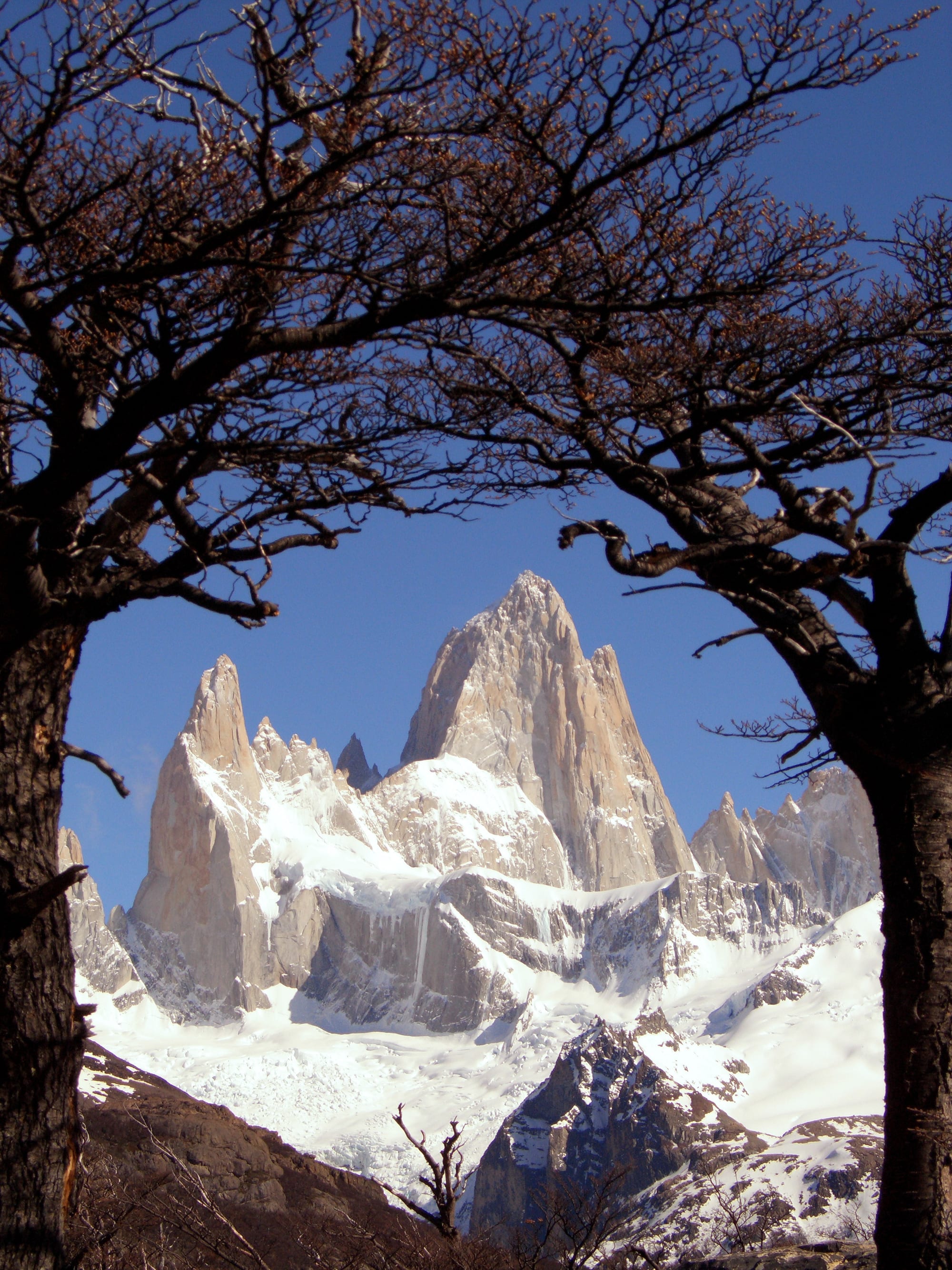 A cluster of sheer granite peaks above an autumn-coloured forest and a still river