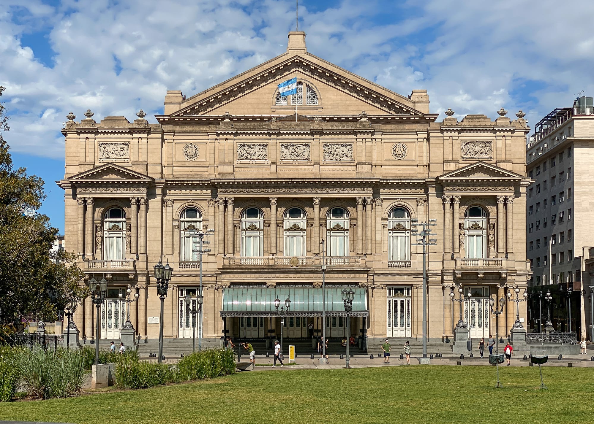 The ornate stone facade of a grand 19th-century opera house on a city avenue