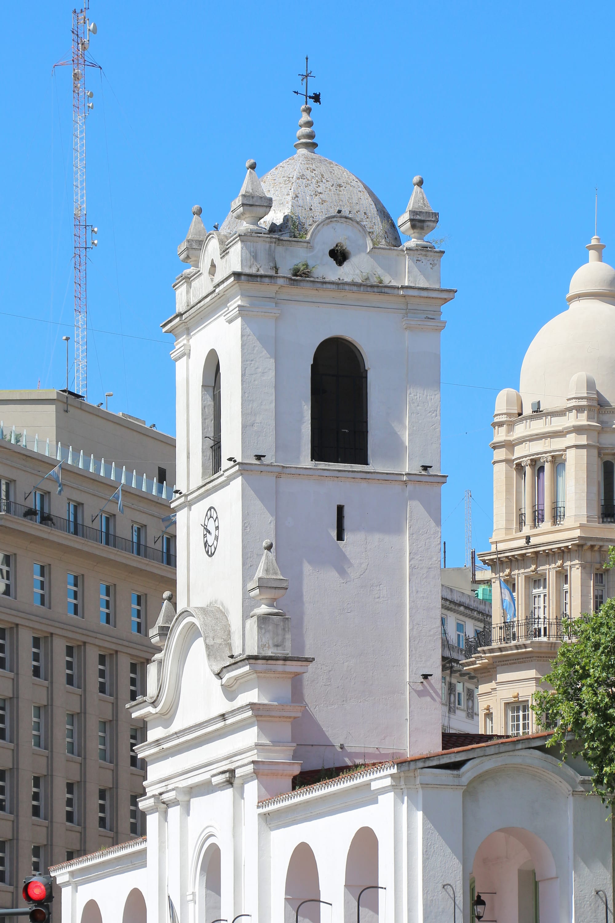 A white colonial town hall with arched arcades and a central bell tower