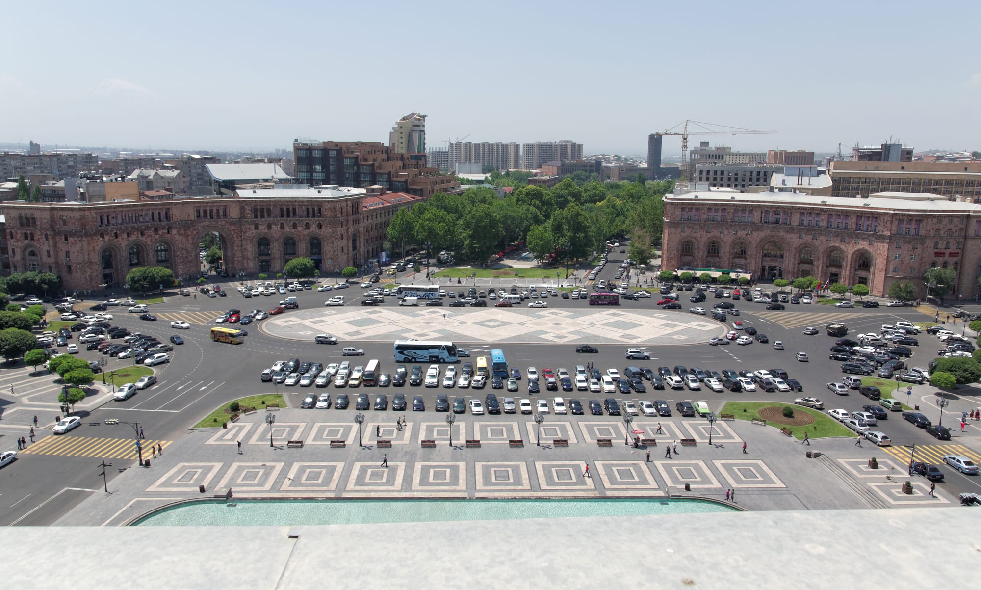 A grand oval plaza ringed by symmetrical pink and cream stone buildings