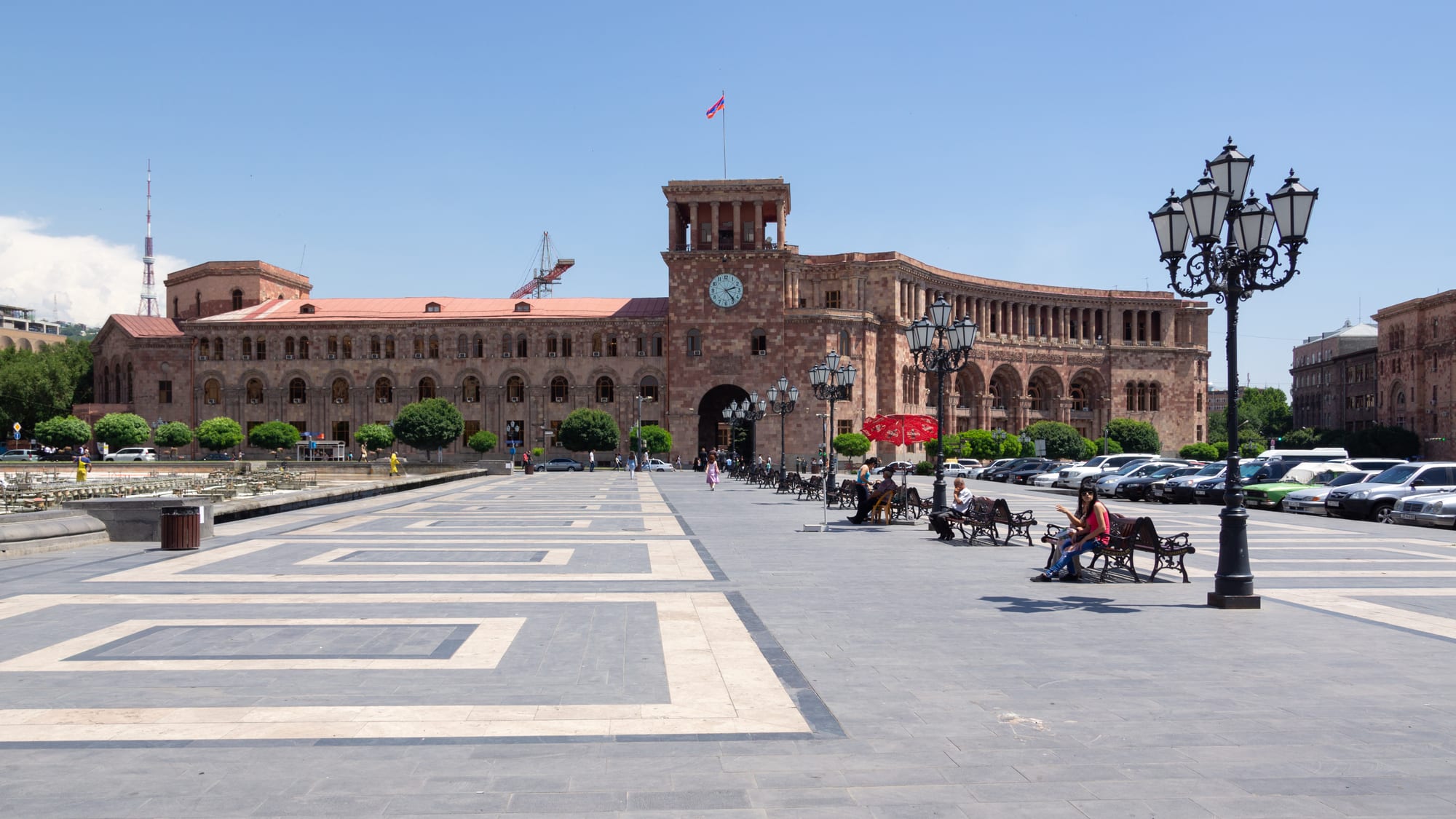 A monumental curved government building of pink and cream stone with arcades and a clock tower