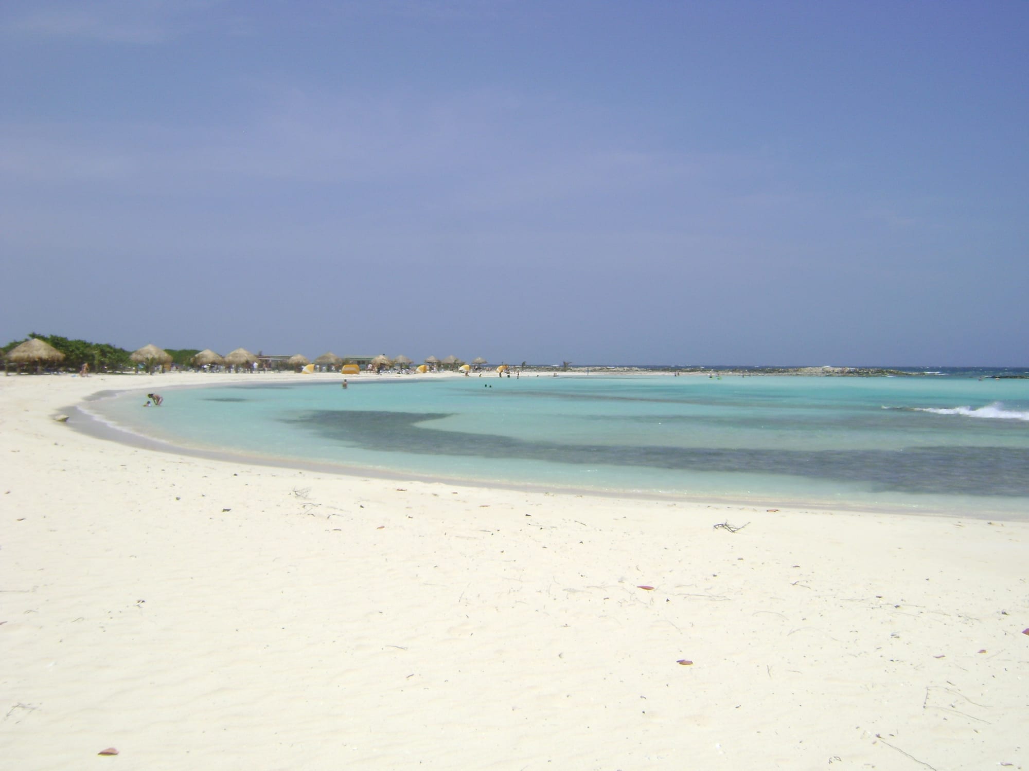 A shallow, calm, almost enclosed lagoon of pale water on a low desert coast