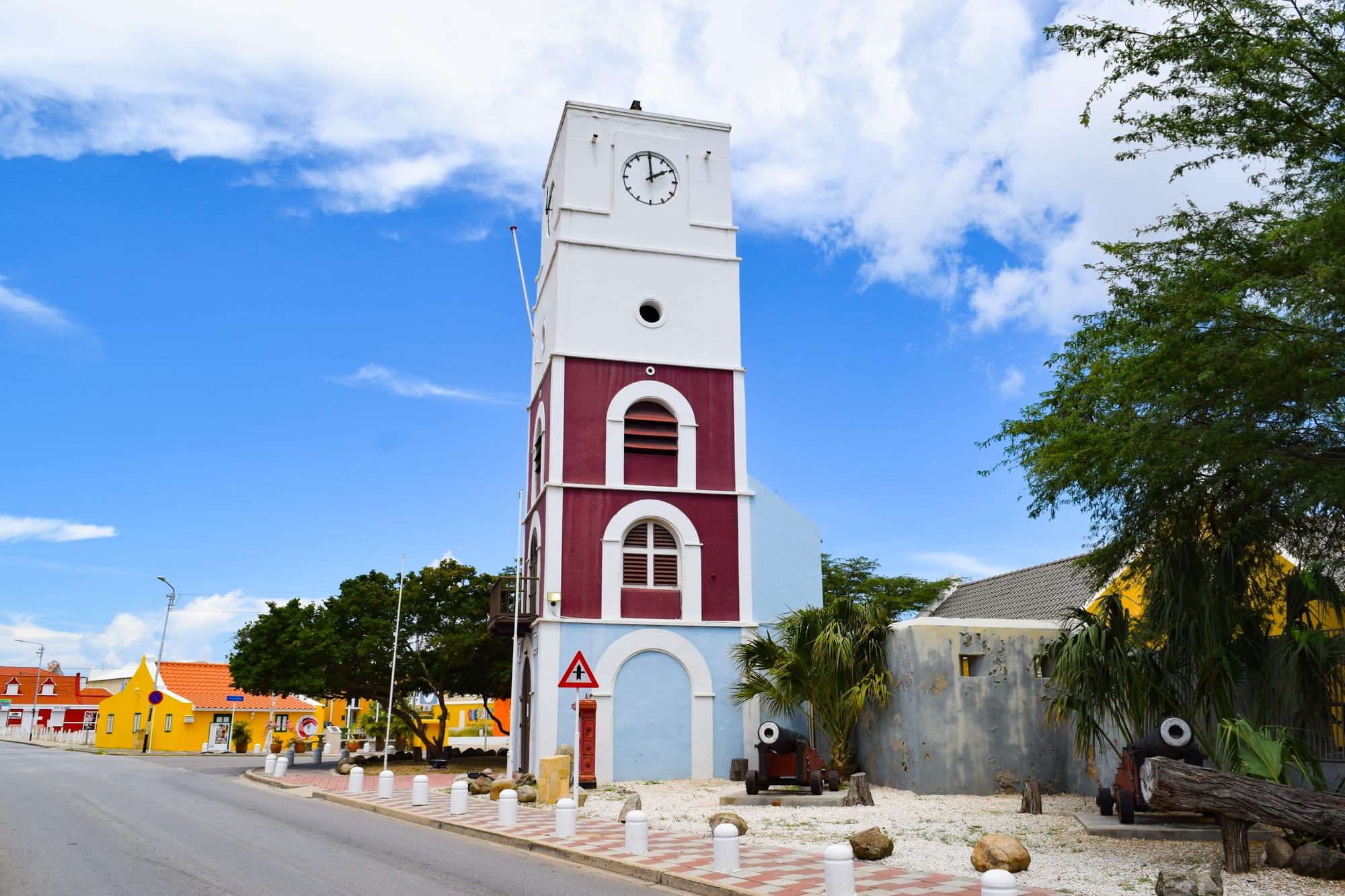 A squat colonial fort with a tall clock-and-bell tower attached, in a town square