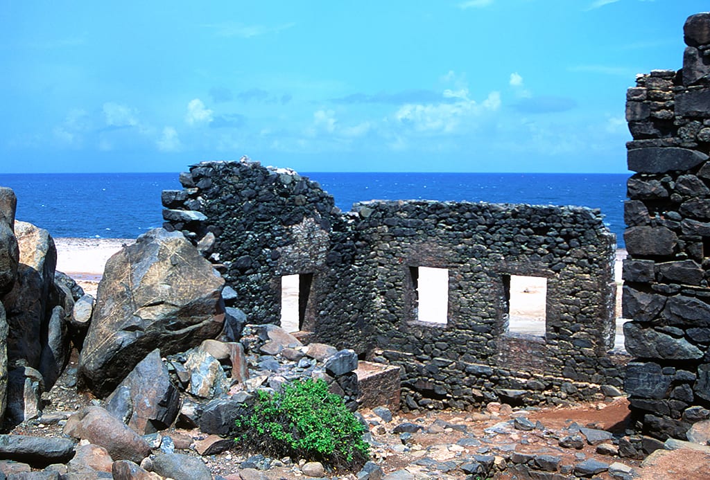 The roofless stone shell of a 19th-century industrial building on a bare coast