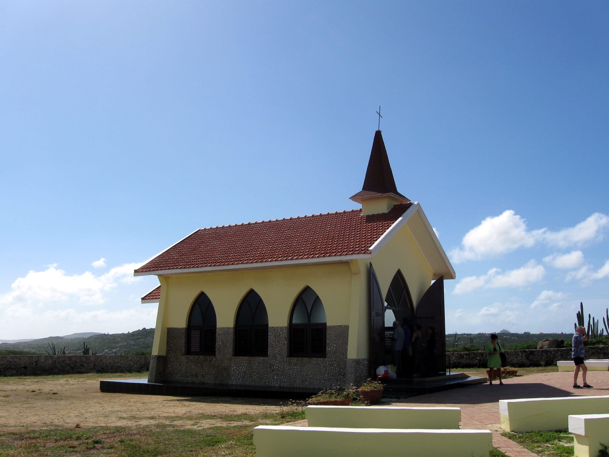 A small bright-yellow chapel with a simple bell gable, alone in cactus scrub