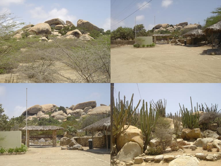 Huge rounded reddish boulders stacked together rising out of flat desert scrub