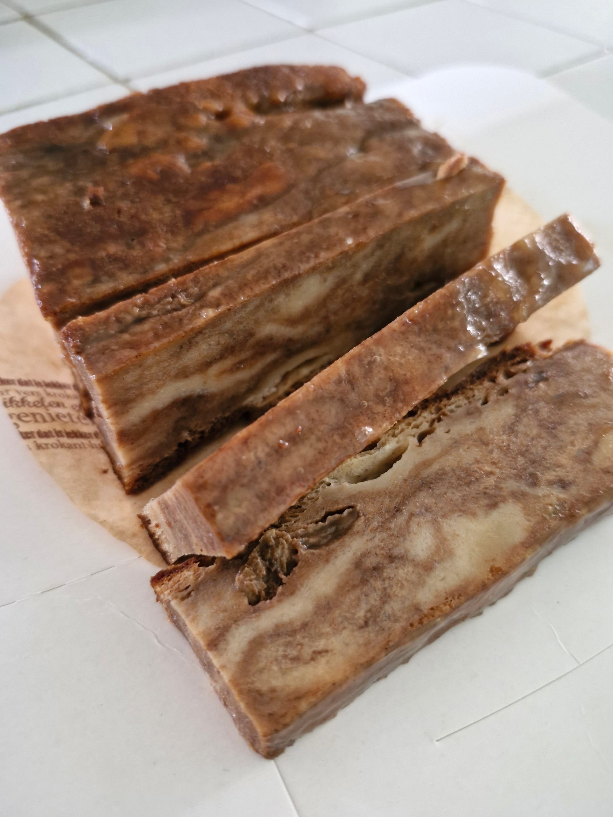 A dense sliced brown loaf with a marbled, peanut-flecked interior, on a countertop