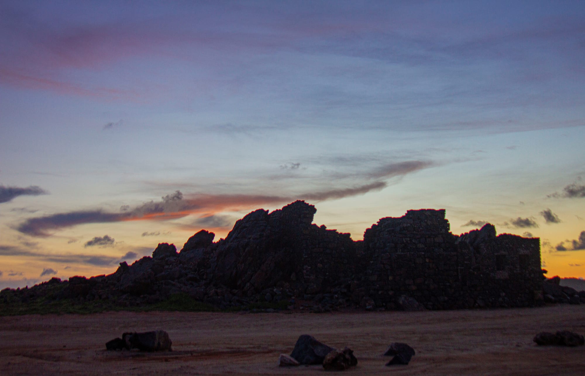 Thick roofless stone walls of a ruined 19th-century industrial building on a rocky coast