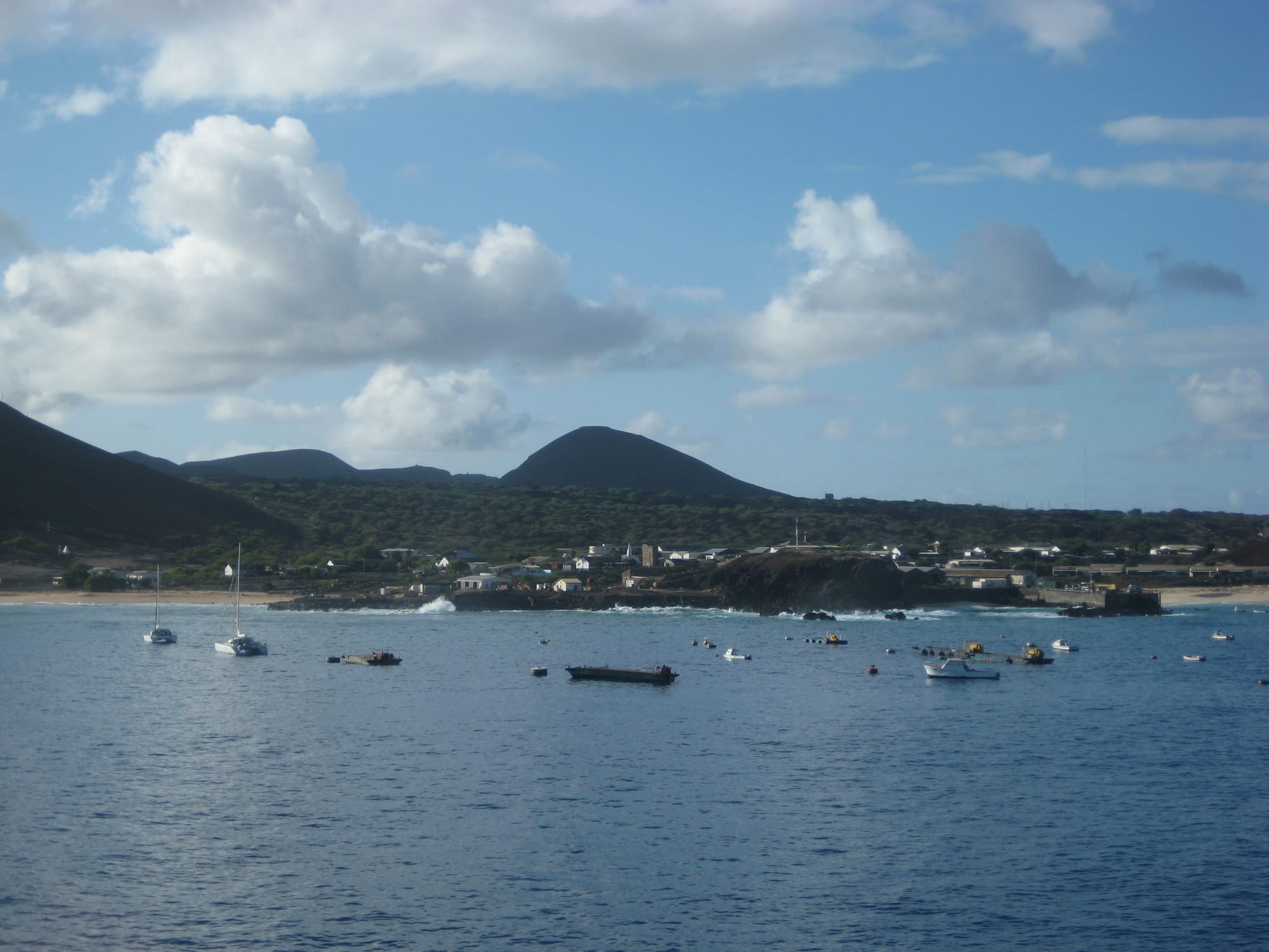 A small settlement of low buildings and a church spire on a dark lava shore