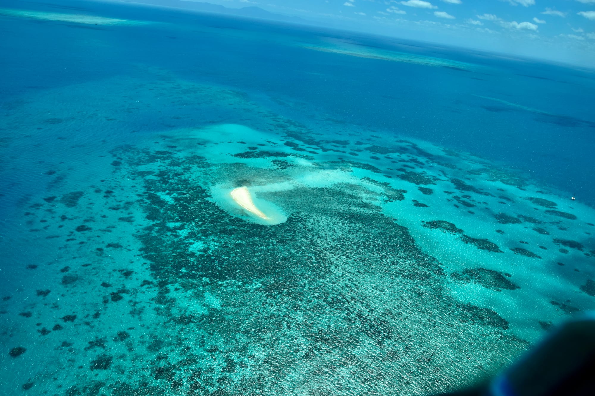 Turquoise and deep-blue reef patterns and sandy cays seen from the air