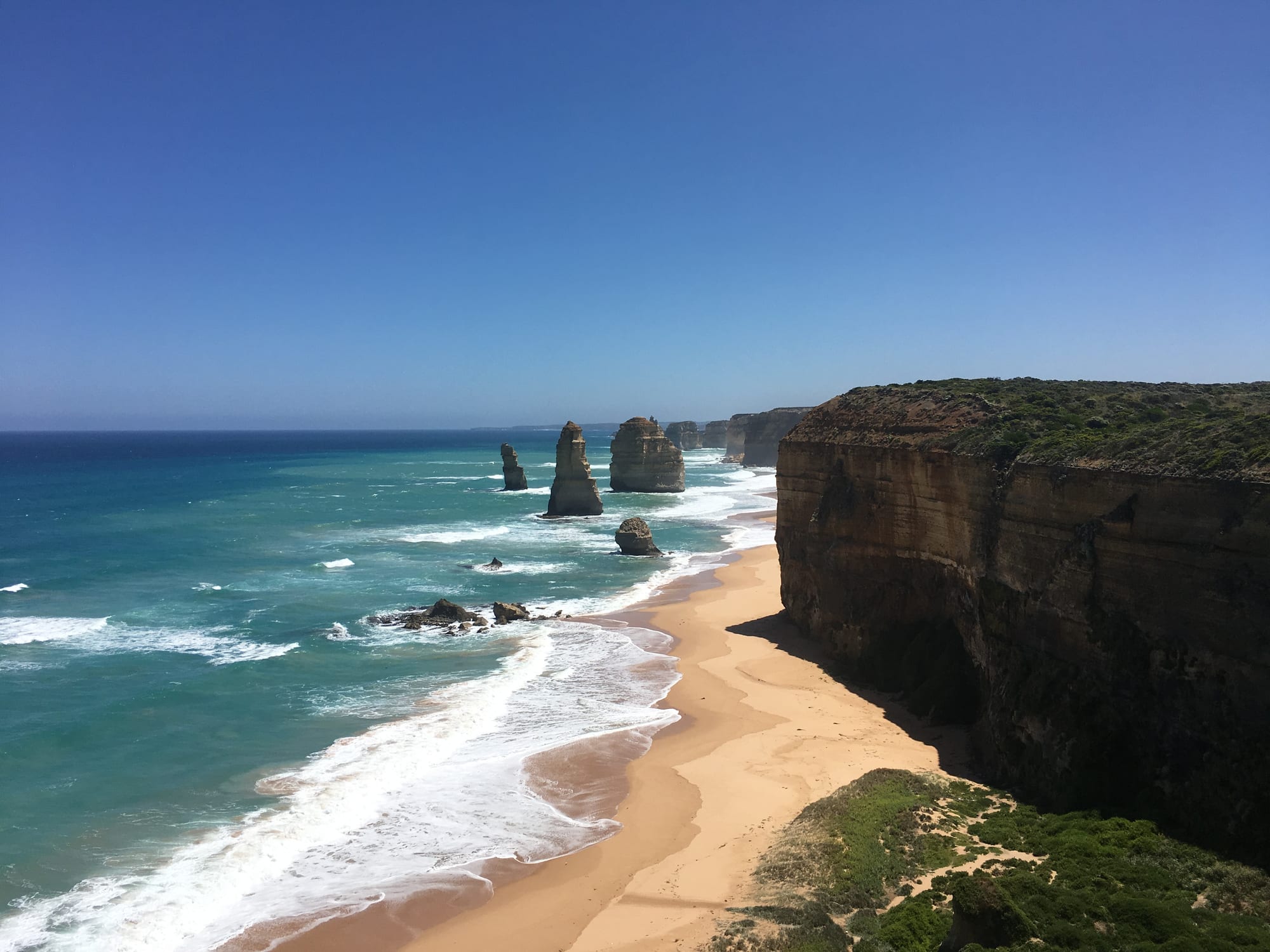 Tall limestone sea stacks standing off eroding orange cliffs above a rough ocean