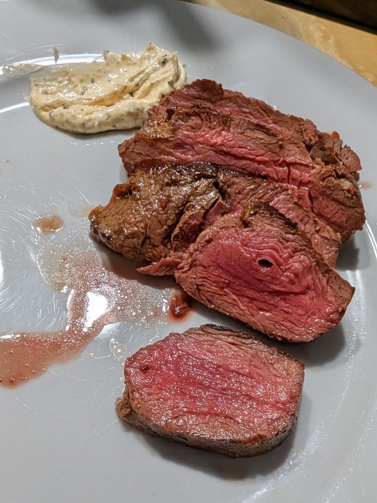 Sliced, pink-centred grilled kangaroo fillet on a plate with a creamy sauce