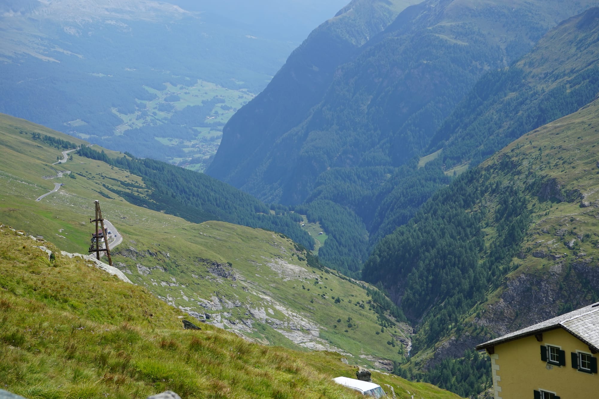 A hairpinning mountain road climbing bare alpine slopes toward snow-streaked peaks