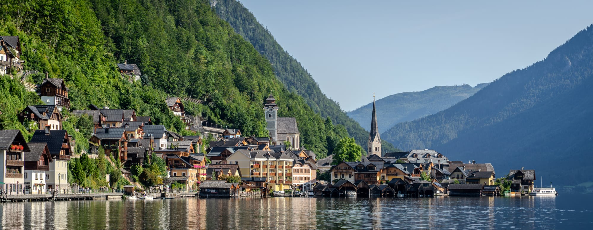 A tiny village of tall pastel houses and a church spire wedged between a lake and steep wooded mountains