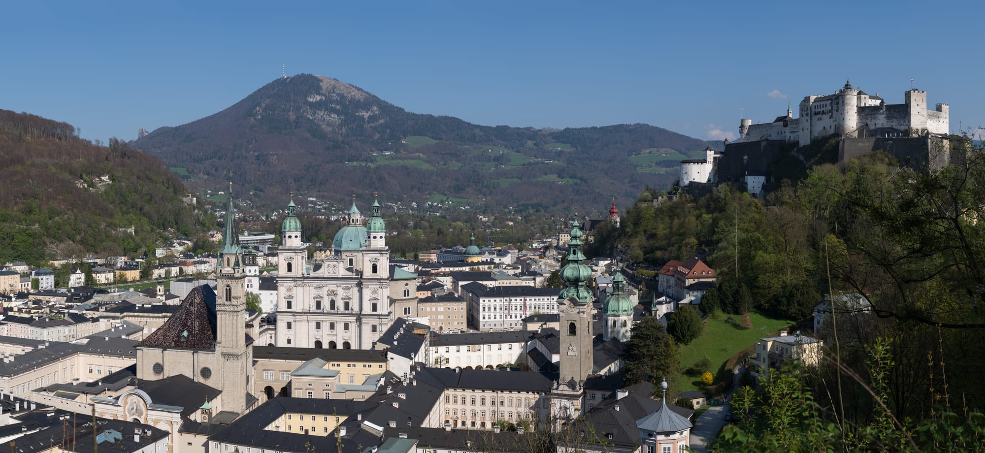 A dense old town of church domes and towers below a large white hilltop fortress
