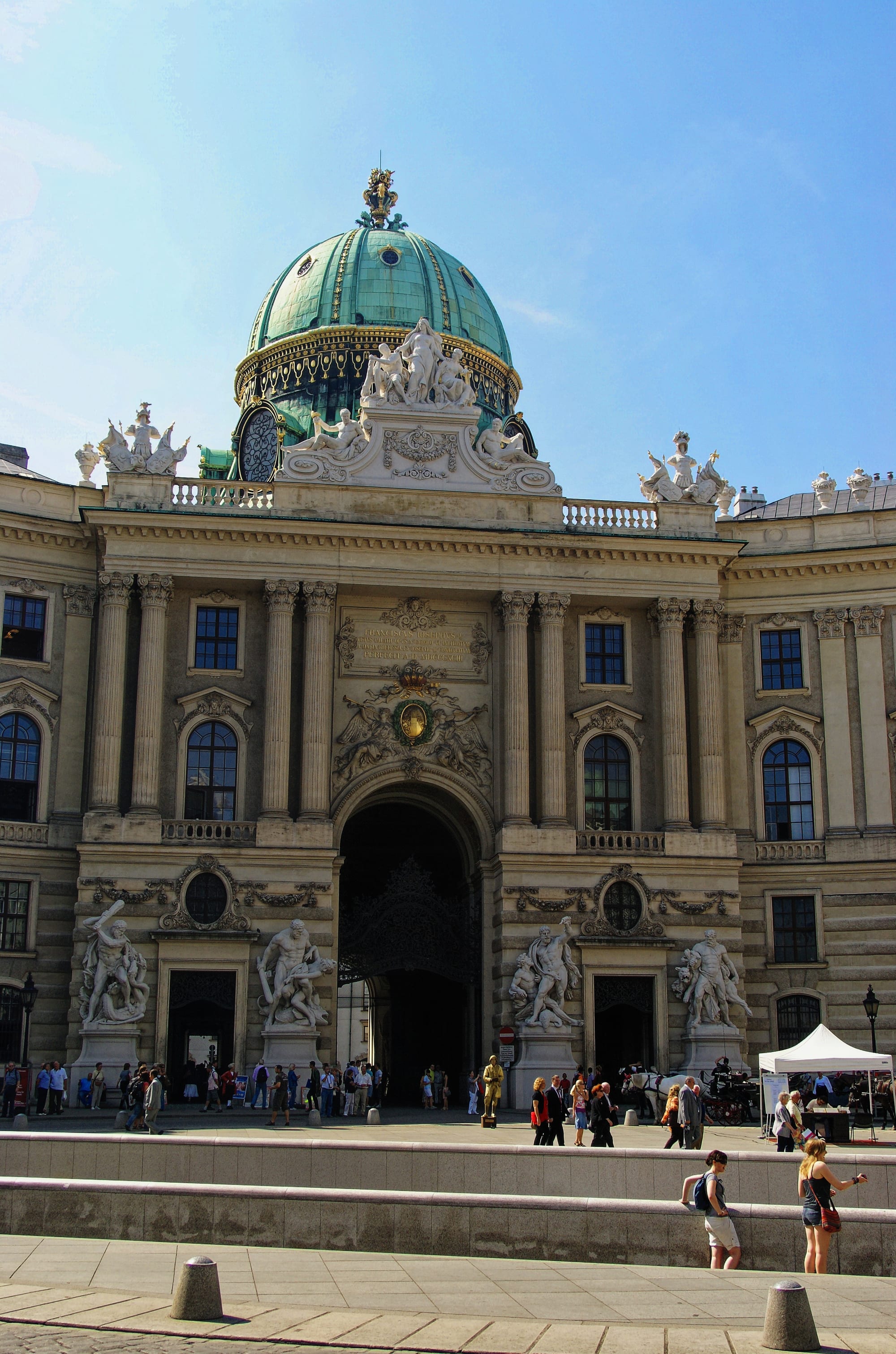A monumental domed baroque palace gateway curving around a city square