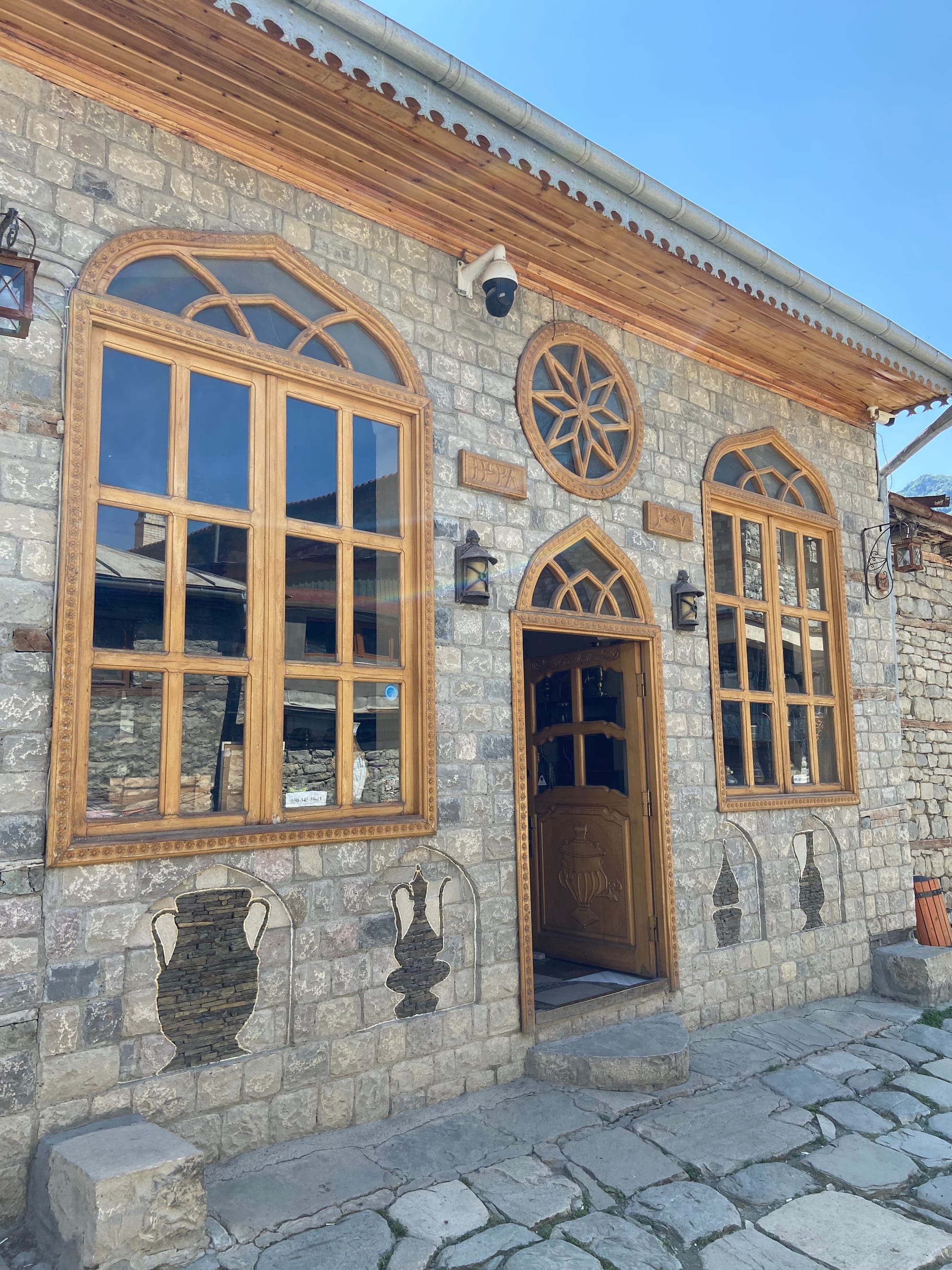 A cobbled village street of stone houses with carved wooden balconies on a mountainside
