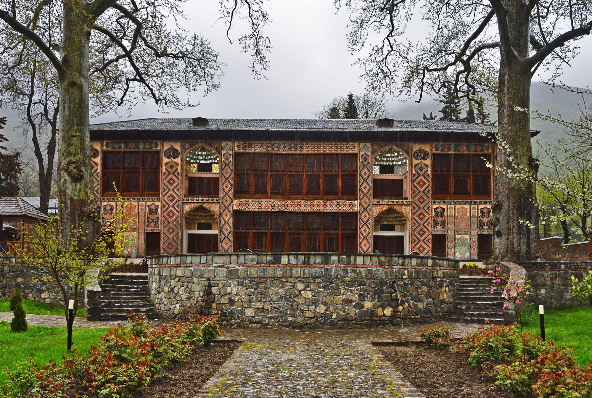 A two-storey palace facade covered in painted patterns and intricate coloured-glass lattice windows