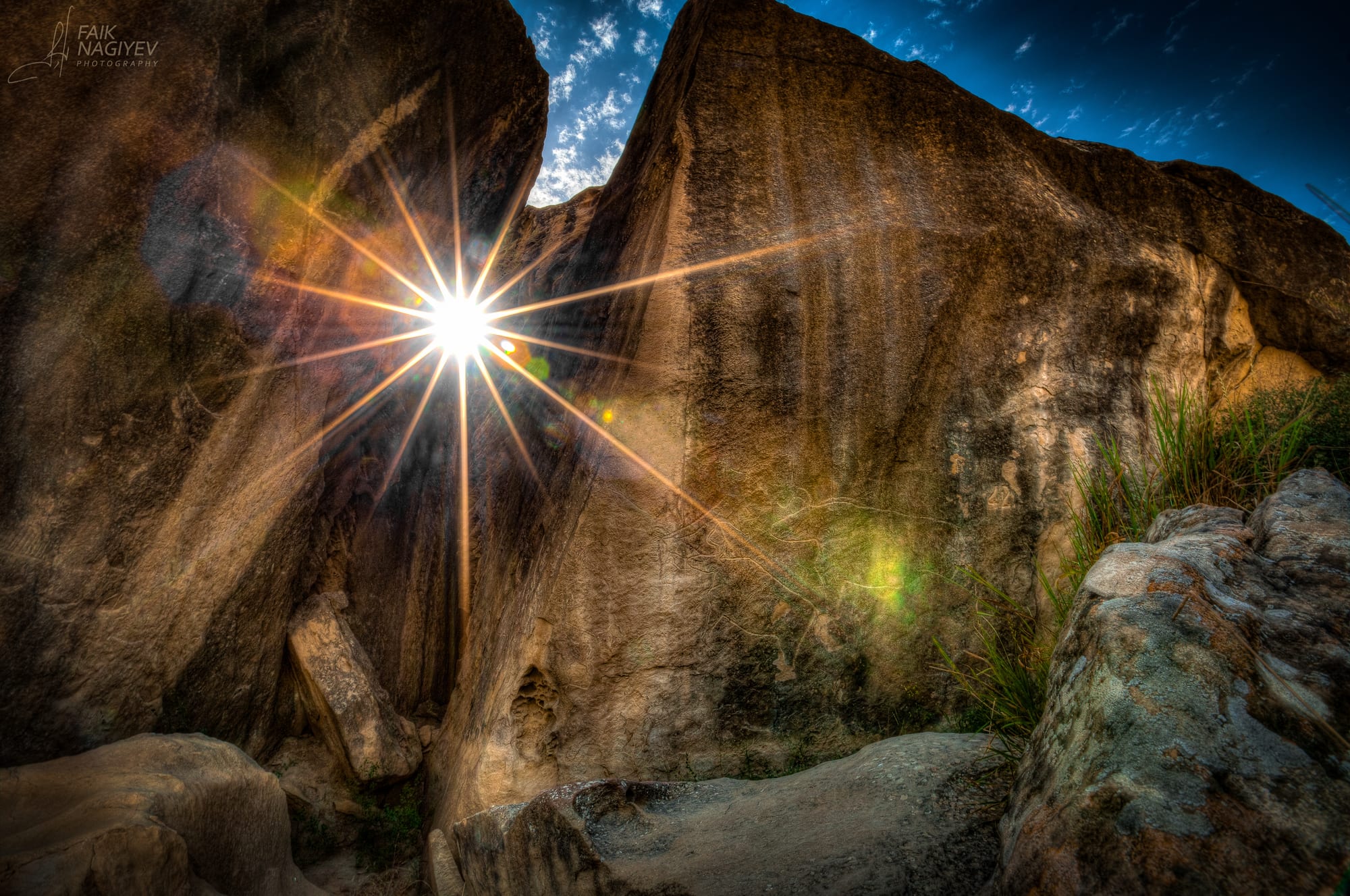 Prehistoric human and animal figures pecked into a large flat rock face