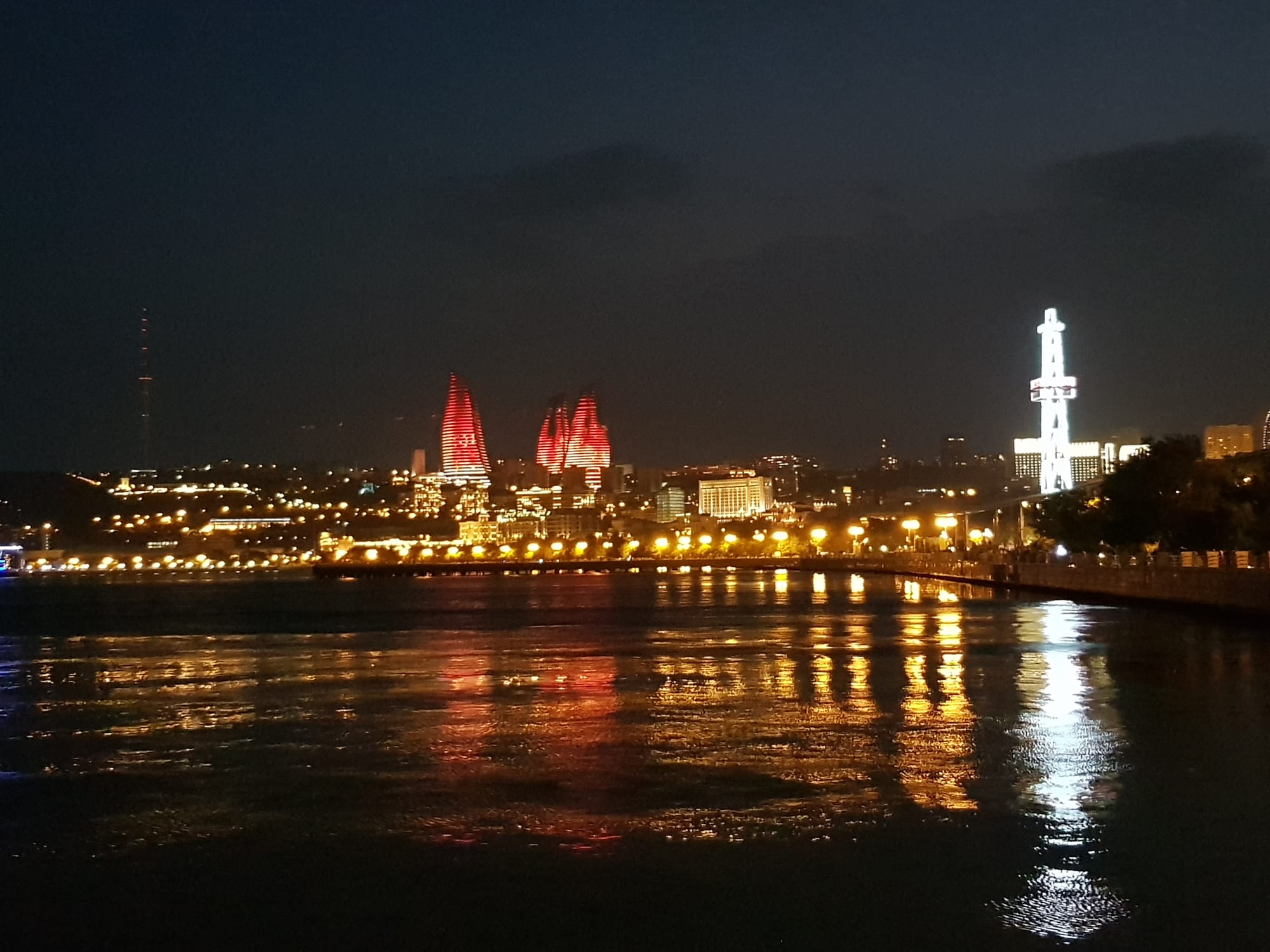 Three tall flame-shaped towers lit up bright red against a night sky