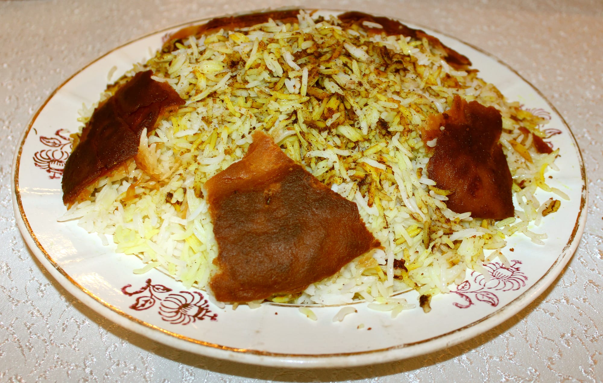 A plate of saffron-tinted rice topped with pieces of golden, crisp fried crust