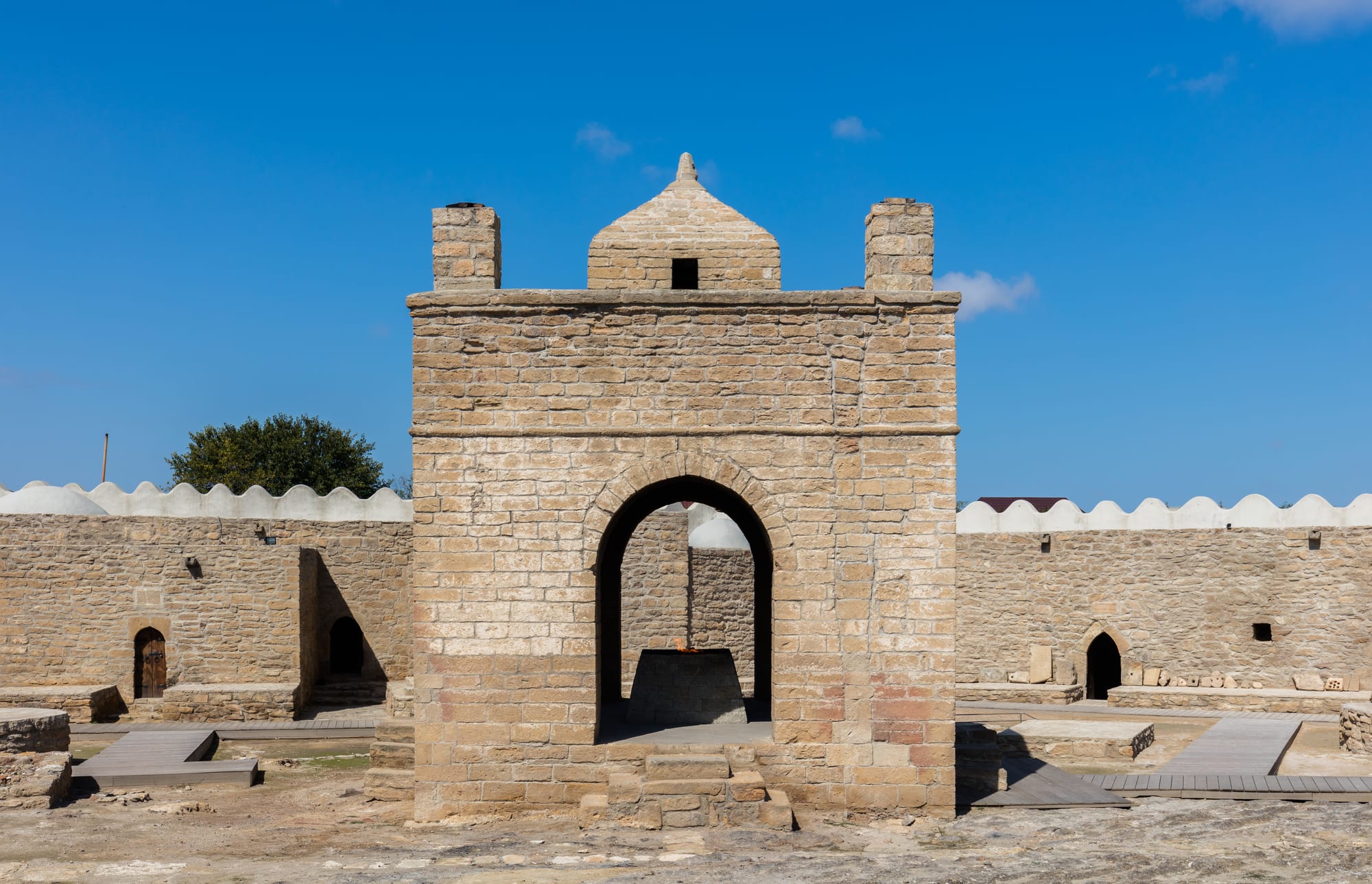 A stone pentagonal courtyard temple with a flame burning at an altar under a central pavilion