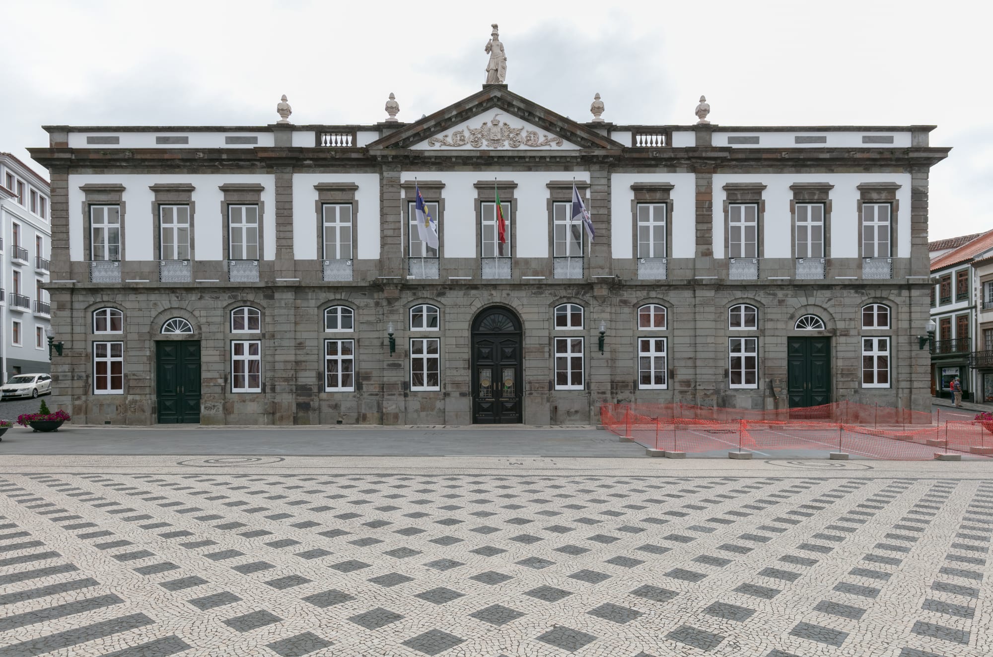 A grand pastel town hall on a cobbled street of low colour-washed buildings